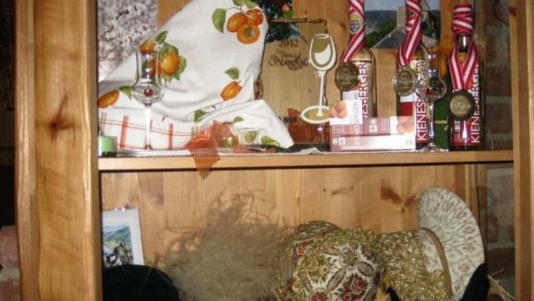 Radlerhof Kienesberger, © Kienesberger Holzregal mit Dekorationen, Likörflaschen und Hüten.