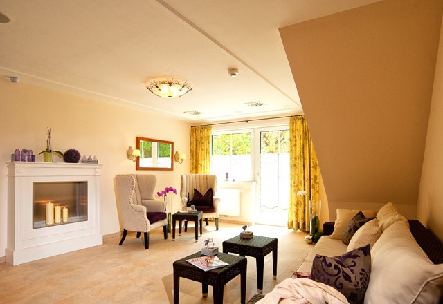 Wellness-Ruhebereich, © Residenz Wachau Ein gemütlicher Wellness-Ruhebereich mit Kamin, Sesseln, Sofa und Tischchen, dekoriert mit Kerzen und Pflanzen.