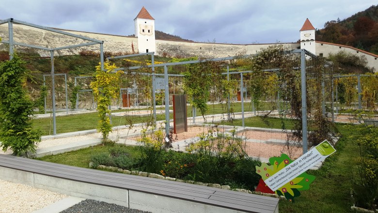 Kartause Aggsbach, © Kartause Aggsbach/Nussbaumer Gartenanlage der Kartause Aggsbach mit Metallstrukturen und Türmen im Hintergrund.