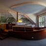 Hotel ResidenzWachau, © Niederösterreich Werbung / Maximilian Pawlikowsky Hotelzimmer mit Bett in Form eines Bootes, Wandgemälde von Landschaft, Fenster mit Vorhängen.
