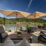 Hotel ResidenzWachau, © Niederösterreich Werbung / Maximilian Pawlikowsky Terrasse mit Blick auf die Donau und umliegende Hügel, ausgestattet mit Sonnenschirmen und Sitzmöbeln.