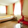 Haus Schiller Patrizia, © Patrizia Schiller Helles Zimmer mit Doppelbett, rotem Sofa und Vorhängen.