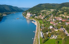 Luftaufnahme von Schönbühel an der Donau mit Schloss und umliegender Landschaft.