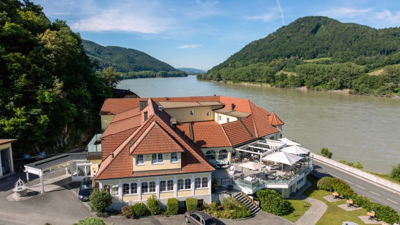 Hotel ResidenzWachau am Flussufer mit umliegenden Hügeln.