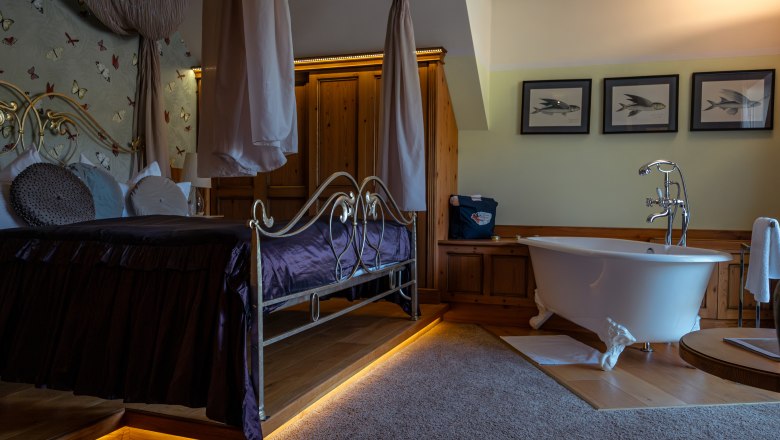 Luxuriöses Hotelzimmer mit Himmelbett und freistehender Badewanne.