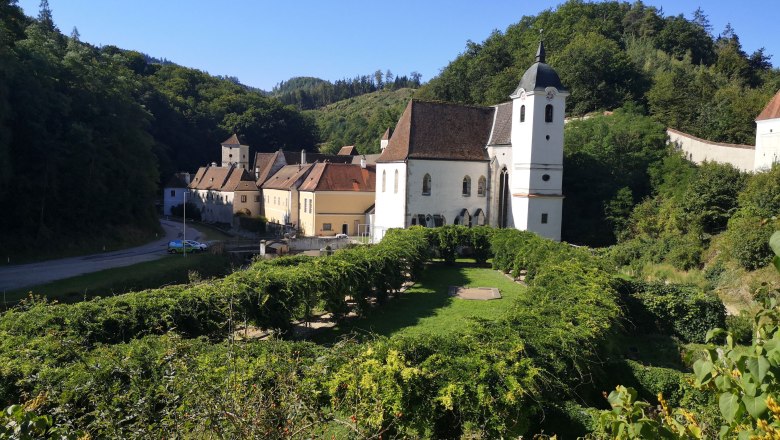 Historische Gebäude und ein Meditationsgarten umgeben von grünen Hügeln.