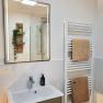 Modernes Badezimmer mit Spiegel, Waschbecken und Handtuchheizk&ouml;rper.