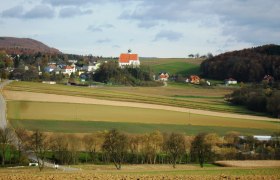 Landschaft mit Kirche und Feldern in Gerolding, Österreich.