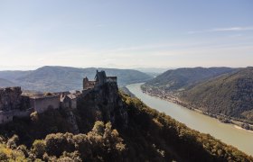 Luftaufnahme der Burgruine Aggstein mit Blick auf die Donau und umliegende Hügel.