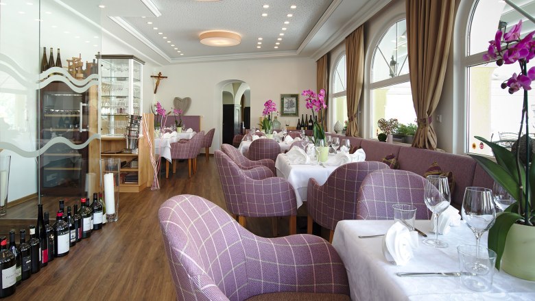 Elegantes Restaurant mit lila karierten St&uuml;hlen, wei&szlig;en Tischdecken und Orchideen.