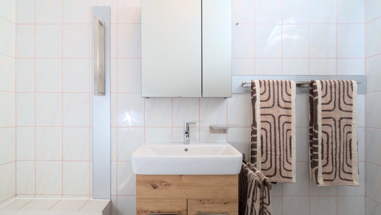 Modernes Badezimmer mit Waschbecken, Spiegel und Handtüchern.